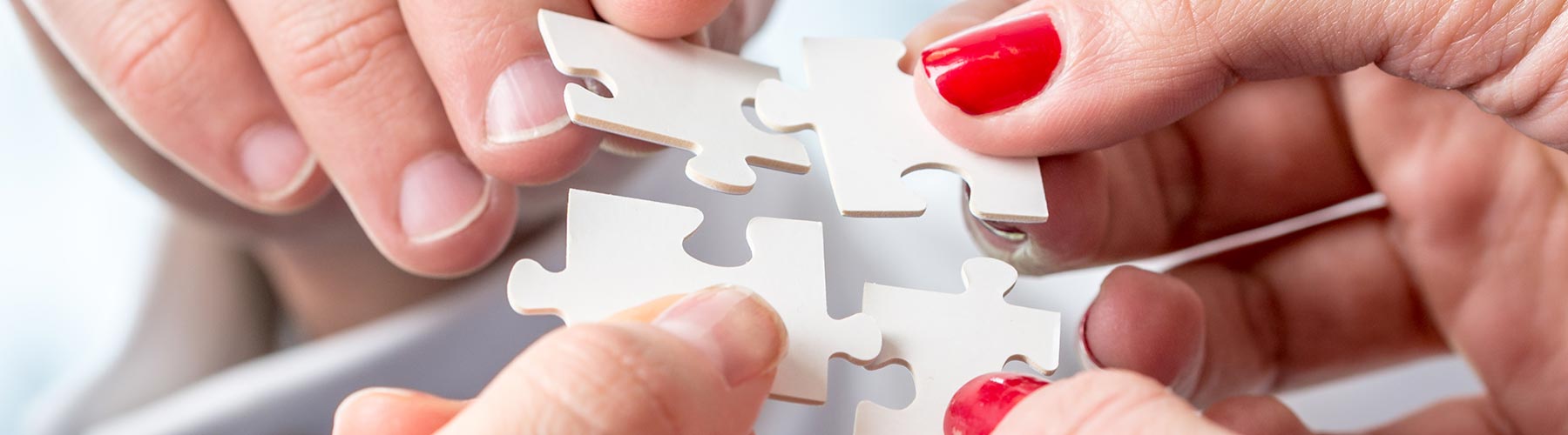 two people fitting four large puzzle pieces together